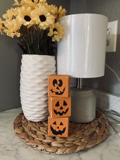 a white vase with yellow flowers in it next to blocks that spell out jack - o'- lanterns