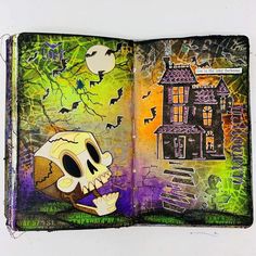 an open book with a drawing of a skull in front of a spooky house