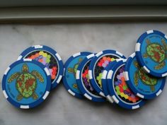 six blue poker chips with colorful sea turtle designs on the front and sides, all stacked together