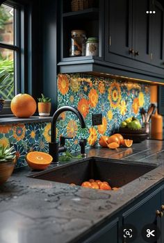 a kitchen sink sitting under a window next to a counter top with oranges on it