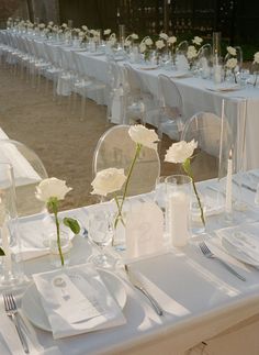 the table is set with white flowers and place settings for guests to sit down at