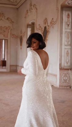 a woman in a white dress is posing for the camera with her back to the camera