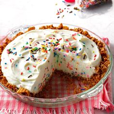 a cake with white frosting and sprinkles in a glass pie dish