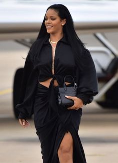 a woman with long black hair walking across an airport