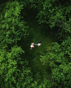 two people are flying through the air in front of some trees and green foliages