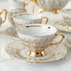 a white and gold tea set sitting on top of a table next to other dishes