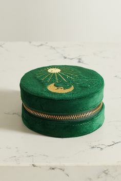 a green hat with gold zippers on top of a marble countertop next to a white wall