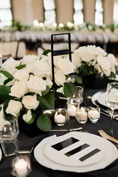 the table is set with white roses, candles and place settings for an elegant dinner