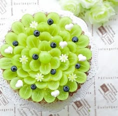 a cupcake decorated with green flowers and blueberries