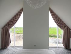 a bed sitting under two windows in a bedroom next to a window covered in curtains