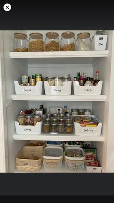 an organized pantry with white shelves filled with food and storage bins on the bottom shelf