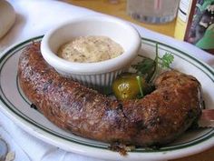 there is a large sausage on a plate with some dipping sauces in the bowl