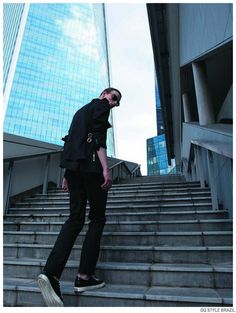 a man standing on some steps with his hand in his pocket and looking up at the sky