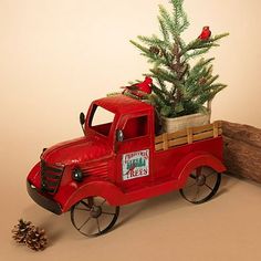 an old fashioned red truck with a christmas tree in the back and pine cones on the side