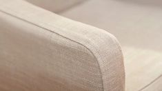 a close up view of the back end of a couch with white linen on it