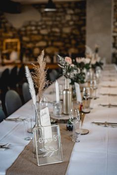 the table is set with silver vases and place settings for guests to sit at