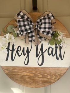 a wooden sign that says hey y'all with two bows on it and some flowers