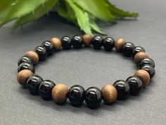 This wood bracelet is made with 7.5mm-8mm natural wood and black glass beads. An appropriate bracelet for men and for women. Makes a nice gift to friend, boyfriend, brother or Dad.  ✔️Bracelet size is the total length of the finished bracelet in inches. For a proper fit bracelet size should be slightly greater than wrist size. Sizing information is intended as a guideline, please order what feel most comfortable on you. These beads are taller than they are wide.  ✔️To measure your wrist, gently Adjustable Black Wooden Jewelry, Black Wooden Beads Bracelet As Gift, Black Wooden Beads Bracelet For Gift, Black Wooden Beaded Bracelets Gift, Black Wooden Beaded Bracelets, Gift Black Wooden Beaded Bracelets, Black Wooden Beads Bracelets For Meditation, Natural Wood And Black, Gift To Friend