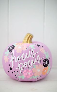 a pink painted pumpkin with flowers and the words hocps ponies on it's side