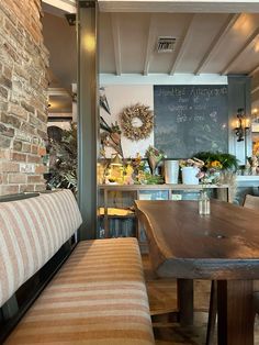 a wooden table sitting in front of a chalkboard on top of a brick wall