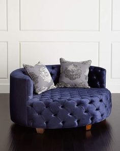 a blue couch with two pillows on it in front of a white paneled wall