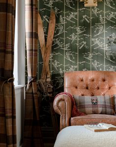 a chair and ottoman in front of a green wallpapered room with wooden utensils