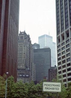 there is a sign that says pedestrians prohibited in front of some tall buildings and trees