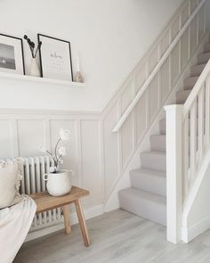 a white room with stairs and pictures on the wall next to a wooden coffee table