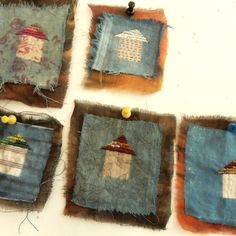 four square pieces of fabric with small houses on them and pins pinned to the sides