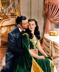 a man in a suit and tie sitting next to a woman wearing a green dress