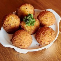 some fried food on a white plate on a wooden table with utensils in it