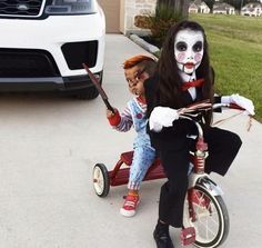 two children in costumes riding on a tricycle