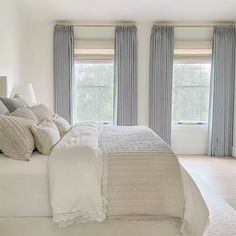 a large bed sitting under two windows in a bedroom