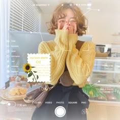 a woman covering her face with both hands and looking at the camera while standing in front of a store window