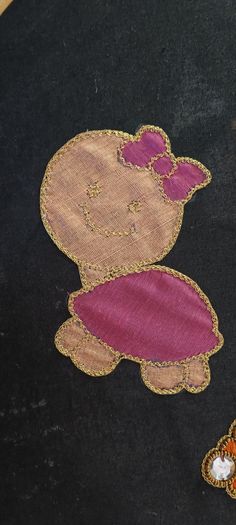 an embroidered teddy bear sitting on top of a black surface