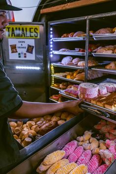 a man is selecting pastries in a bakery