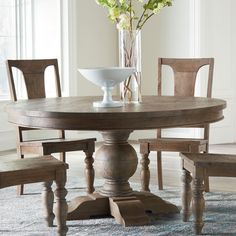 a dining room table with four chairs and a bowl of flowers on the top of it