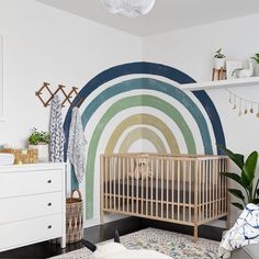 a baby's room with a rainbow wall mural