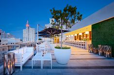 an outdoor seating area with tables, chairs and umbrellas on the roof of a building