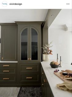 a kitchen with green cabinets and white counter tops