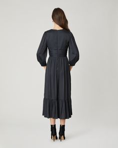 Gorgeous black satin midi dress. This style features a v-neckline with a fitted bodice, decorative buttons at the center front, shirring at the shoulder and waistband, ¾ length balloon sleeves with encased elastic at the openings, and a shirred full midi skirt with bottom ruffle flounce. Bodice lined. Sleeves and skirt unlined. Hidden back zipper. 100% Polyester. Dry clean or hand wash. Color: Jet Elegant V-neck Midi Dress With Elastic Sleeves, Elegant V-neck Dress With Smocked Bodice, Elegant Knee-length Dress With Gathered Waist, Evening Midi Dress With Elastic Sleeves, Formal Knee-length Dress With Elastic Sleeves, Spring Evening Puff Sleeve Dress With Smocked Bodice, Chic Empire Waist Midi Dress With Ruched Bodice, Chic Midi Dress With Ruched Bodice And Empire Waist, Evening Midi Dress With Balloon Elastic Sleeves