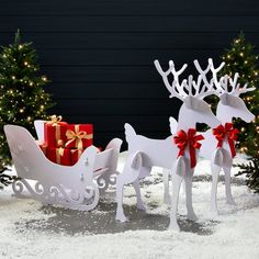 two white reindeer sleighs with red bows and presents