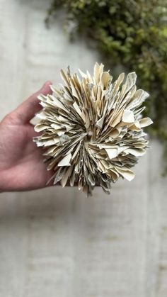 a person is holding up a piece of paper that has been folded in the shape of a flower