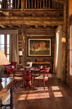 a living room filled with lots of furniture and wooden beams on the ceiling, along with large windows