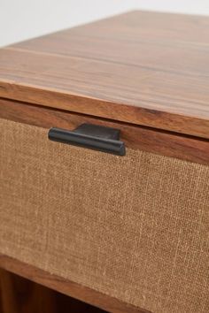 a close up of a drawer on a wooden table with a black object in it