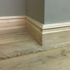 the corner of a room with wood flooring and gray paint on it's walls