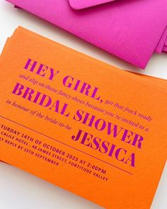 an orange and pink bridal shower card next to some envelopes on a white surface