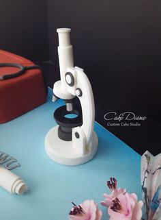 a cake with a microscope on it and some flowers in front of the cake stand