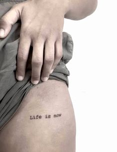 a person with a tattoo saying life is now on their lower thigh and the word'life is now'written in black ink