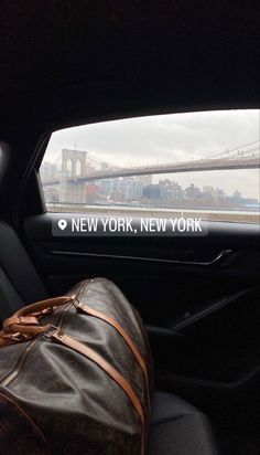 the back seat of a car with luggage in front of it and a view of the brooklyn bridge